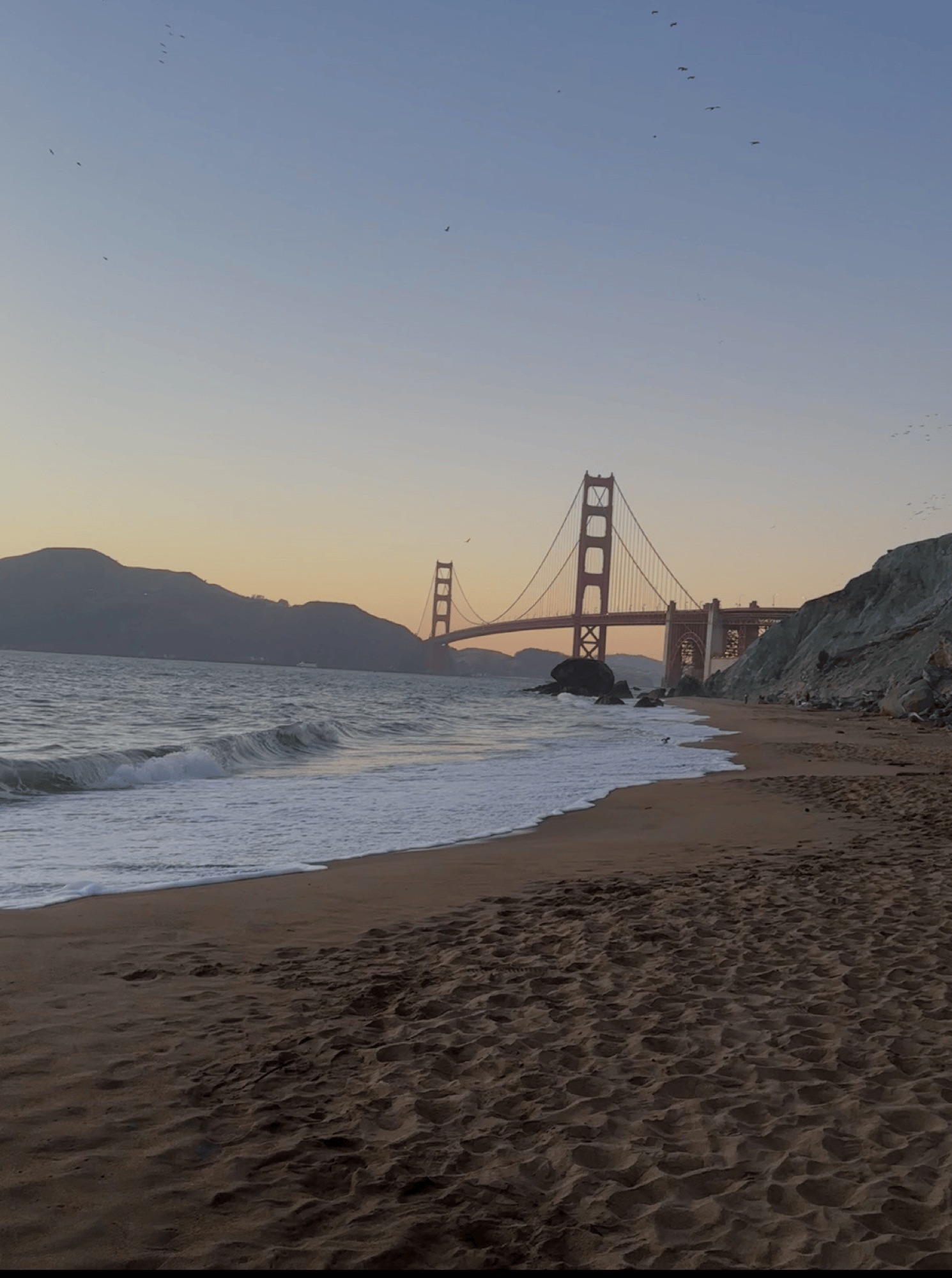 the Golden Gate Bridge at dusk seen from the sand at Baker Beach