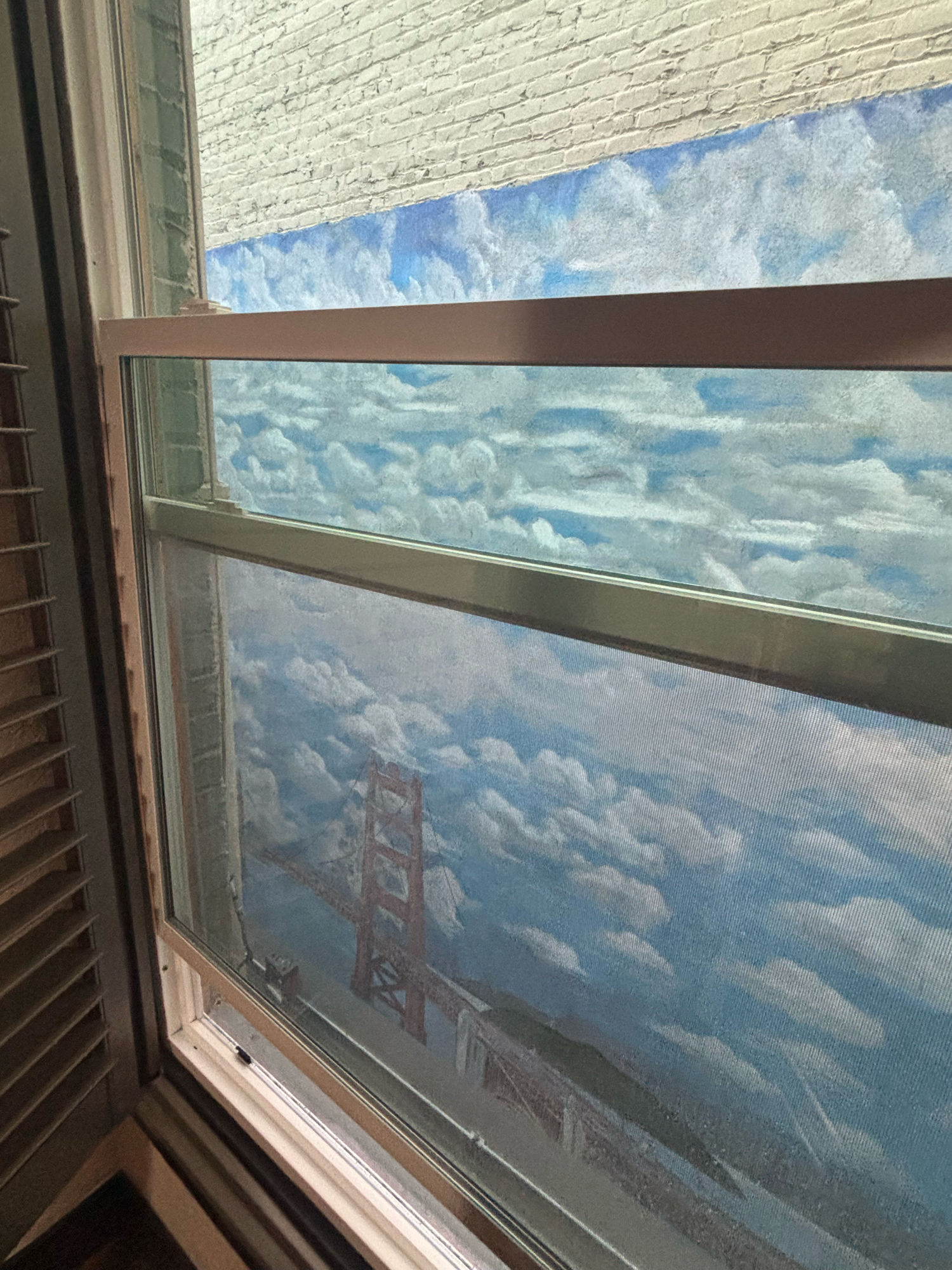 a mural of the Golden Gate Bridge painted on a wall outside the hotel window