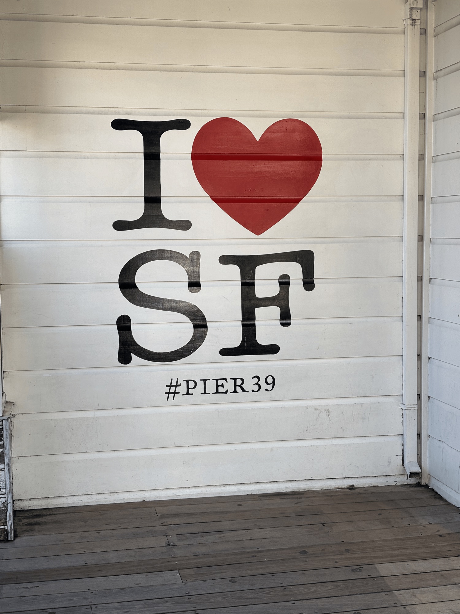 an I heart SF sign painted on a white wall at Pier 39