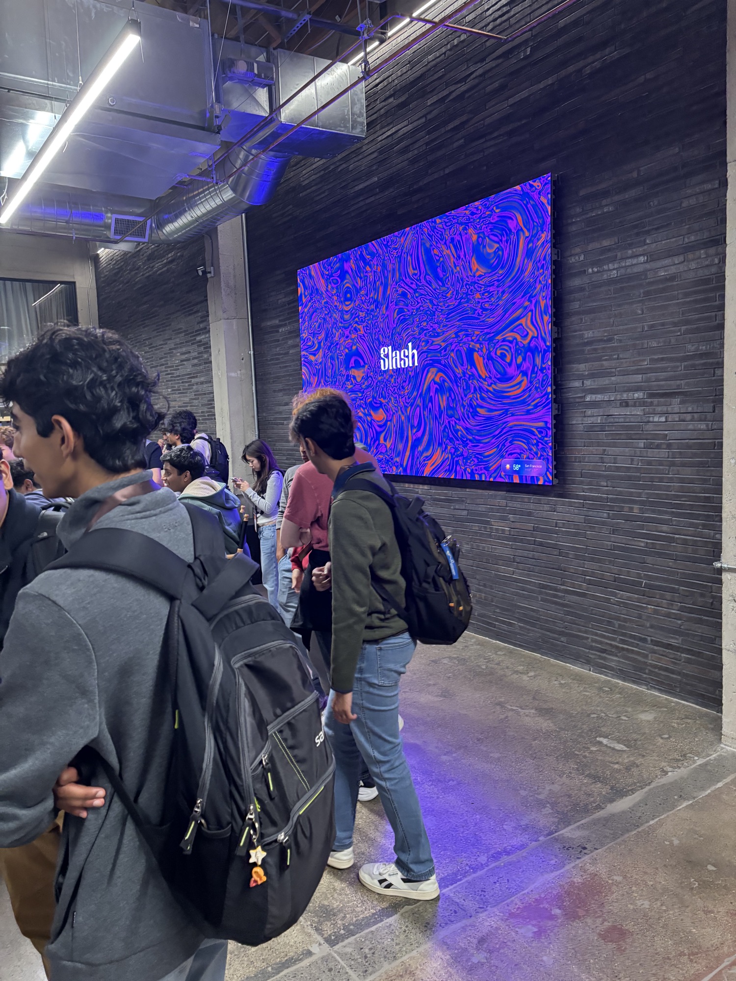 a large screen showing the Slash logo on a brick wall inside Slash HQ
