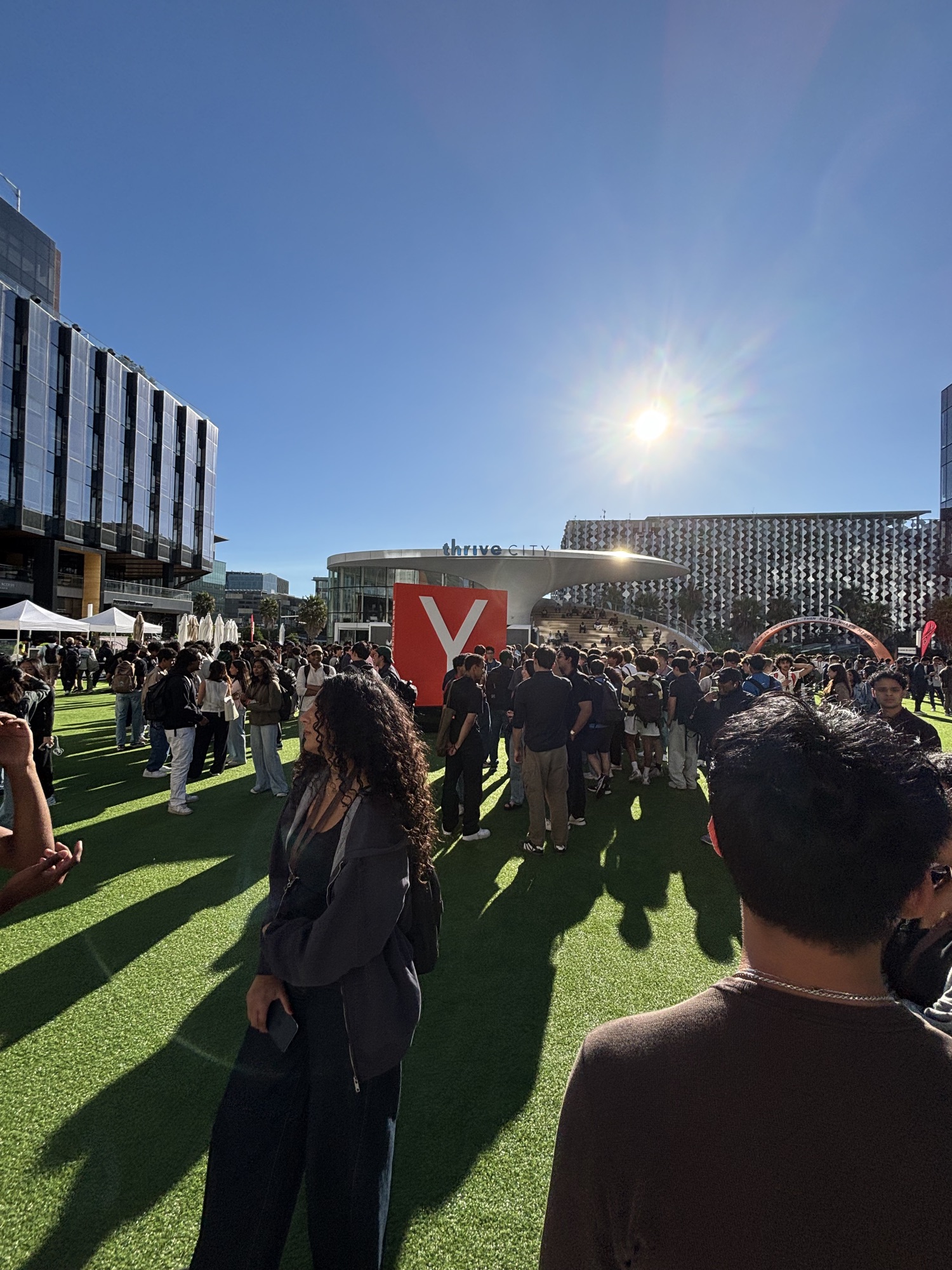 a big red Y Combinator sign on the Thrive City lawn outside the Chase Center with a crowd around it