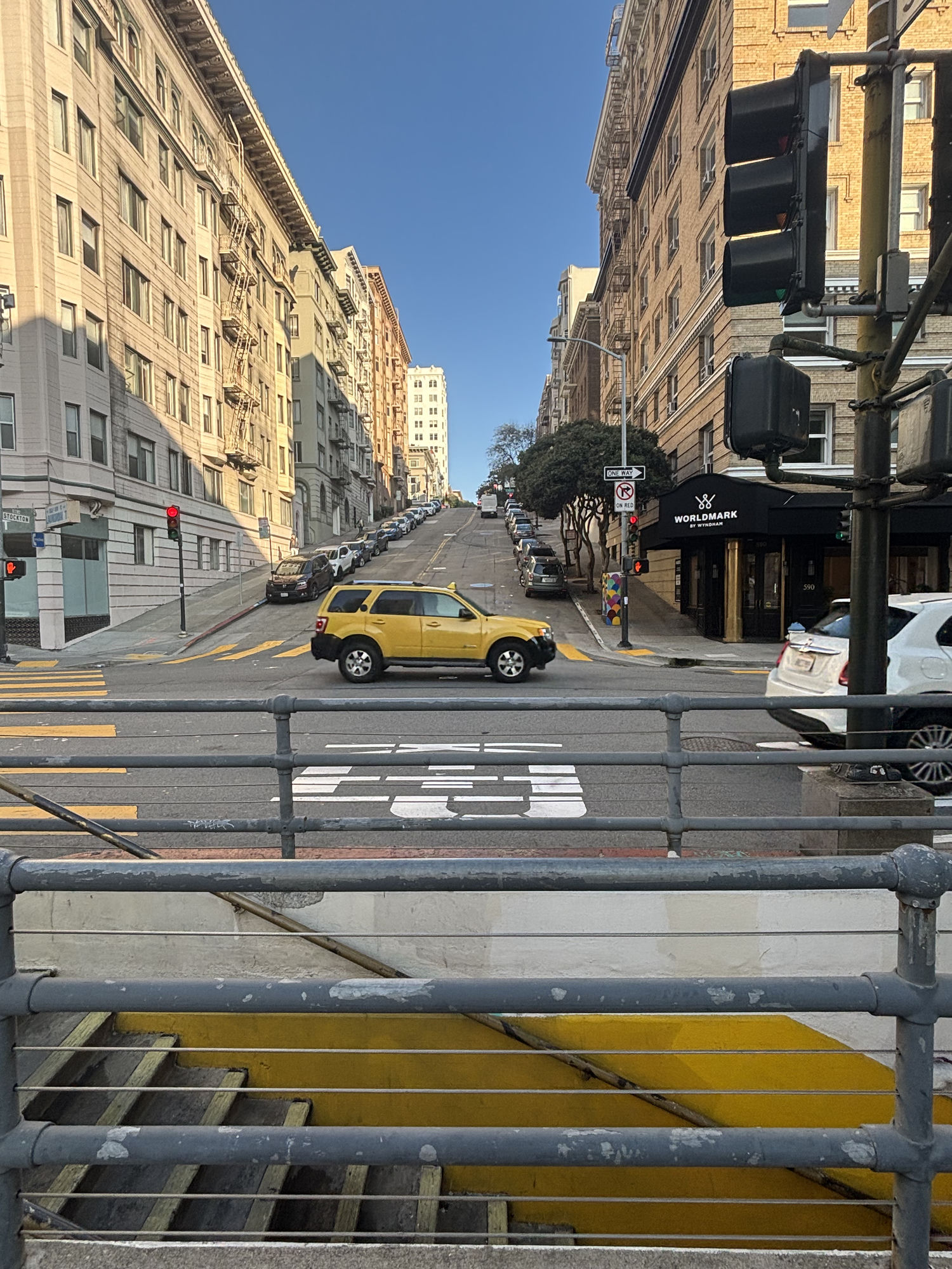 a yellow car crossing a steep San Francisco street